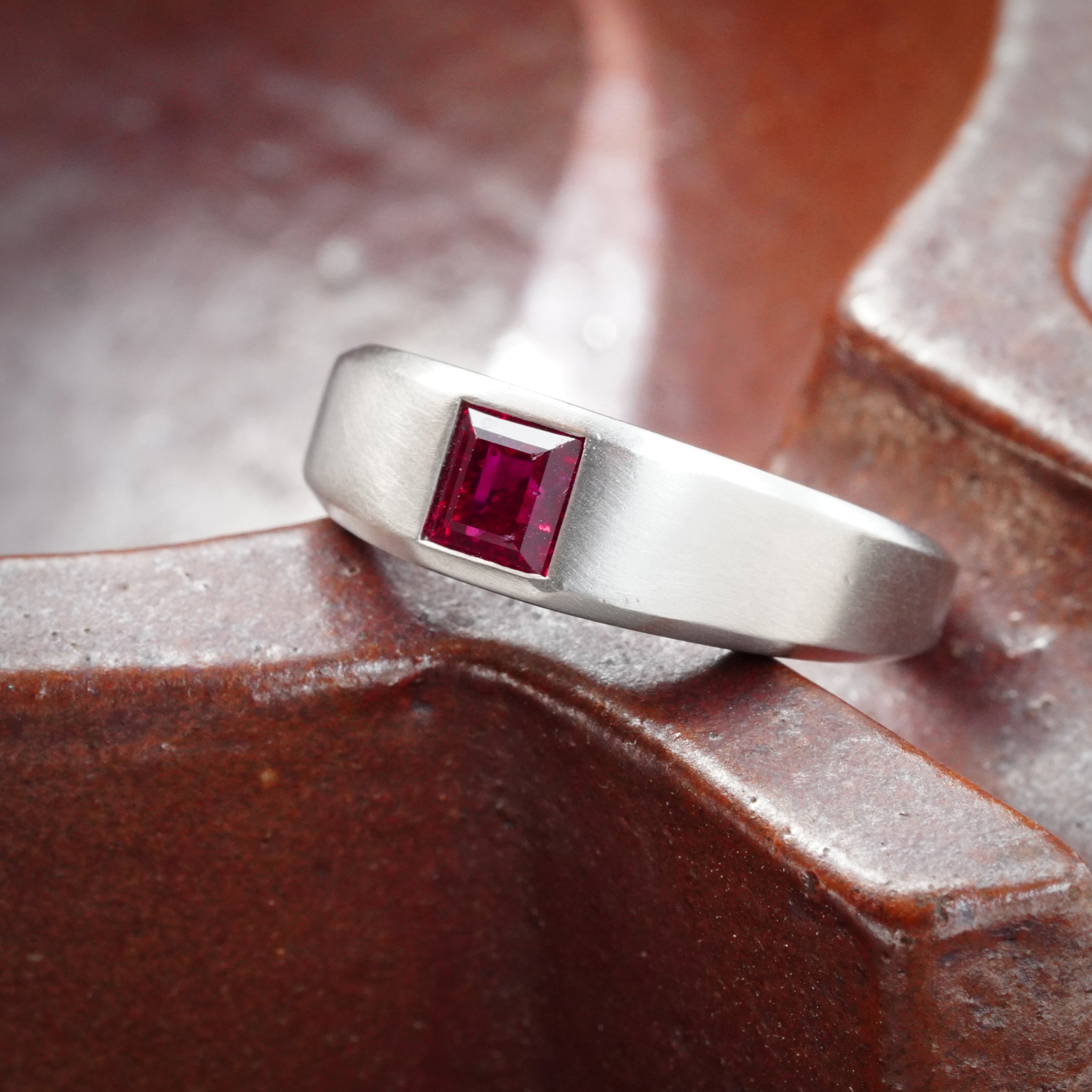 Side view of our 1.15-carat step-cut Burmese ruby ring, featuring a clean red gemstone set in a platinum flush setting, presented by Jogani.