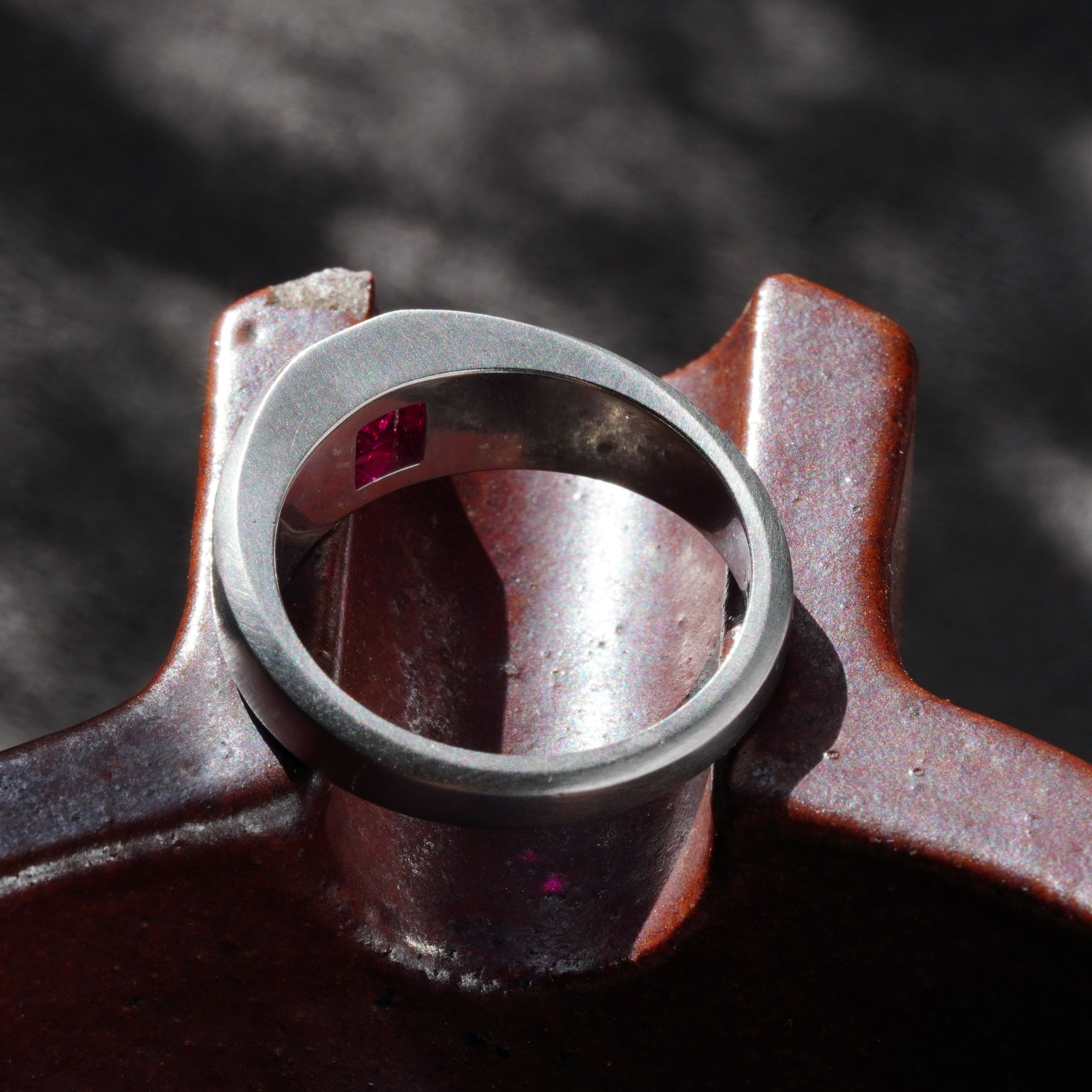 Top-down view of a 1.15-carat step-cut Burmese ruby ring, highlighting the clean red gemstone and platinum flush setting, presented by Jogani.