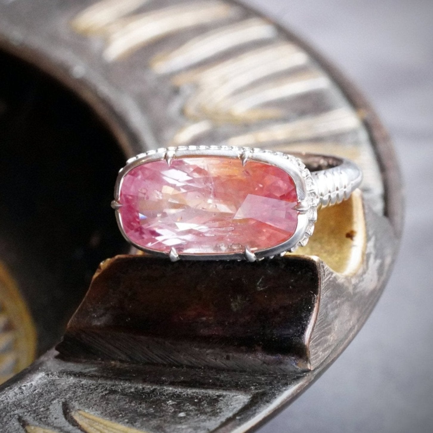 Rare and exquisite, this no-heat 10.52 ct Ceylon Padparadscha sapphire ring showcases a mesmerizing orangy-pink glow, elegantly set in platinum by Jogani.