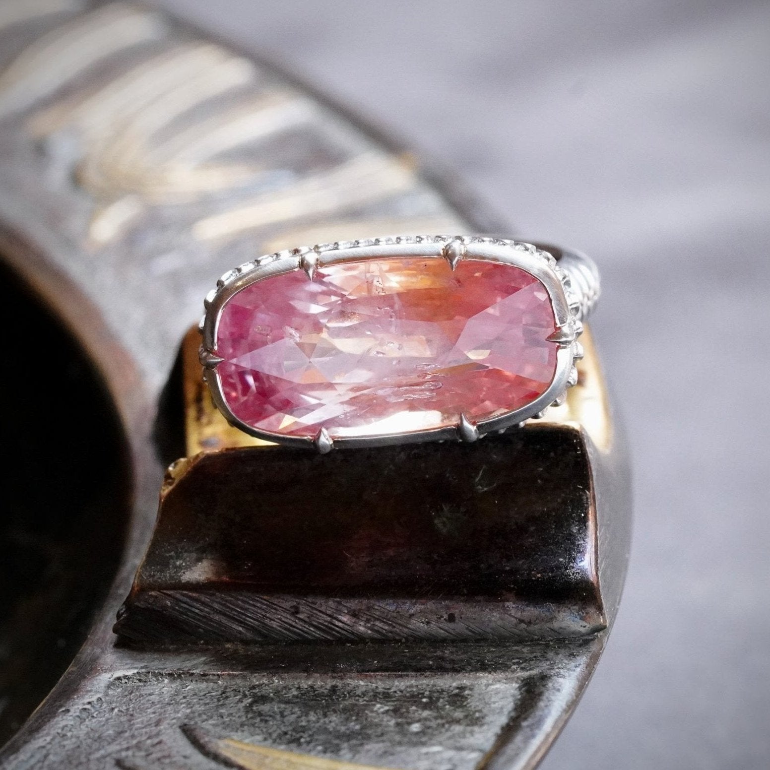 A breathtaking 10.52 ct cushion-cut Ceylon Padparadscha sapphire ring, no heat, with a vibrant orangy-pink hue, set in a platinum collet setting by Jogani.