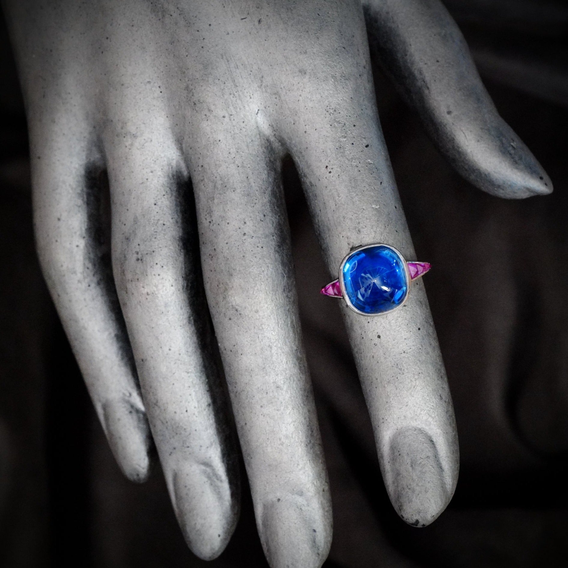 Jogani presents an extraordinary 10.99 ct no-heat Burma sapphire ring, featuring a rich blue sugarloaf-cut gem surrounded by rubies in a platinum setting.