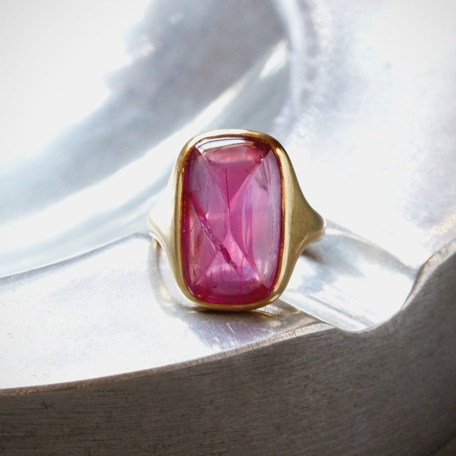 A luminous 12.00 ct sugarloaf-cut Burma ruby, no heat, radiating deep pink brilliance. Set in elegant 18K gold, this extraordinary ring is a coveted collector’s piece.