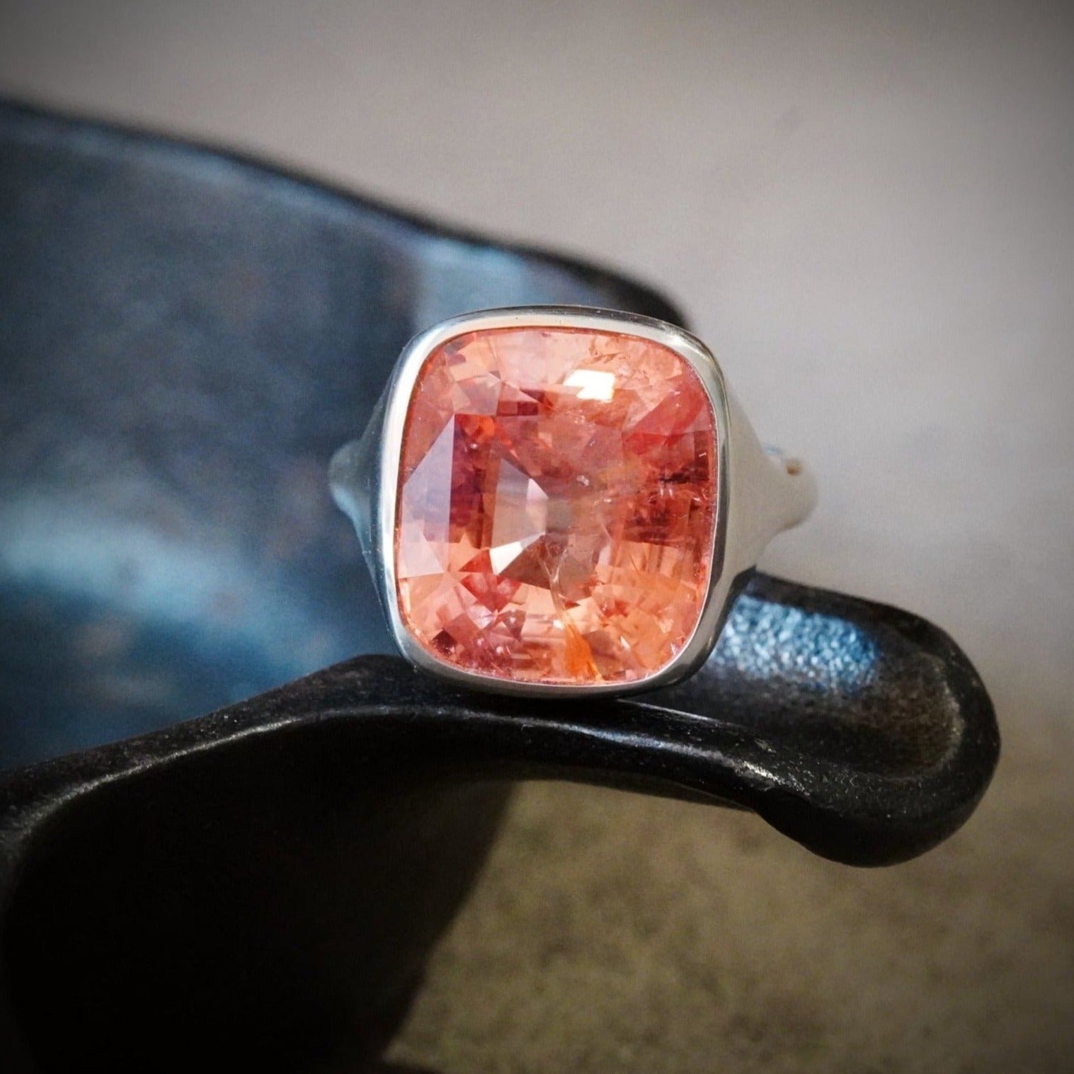 A magnificent 12.42 ct cushion-cut Ceylon Padparadscha sapphire ring, set in a 20K platinum bezel by Jogani. A rare no-heat gemstone for collectors and connoisseurs.