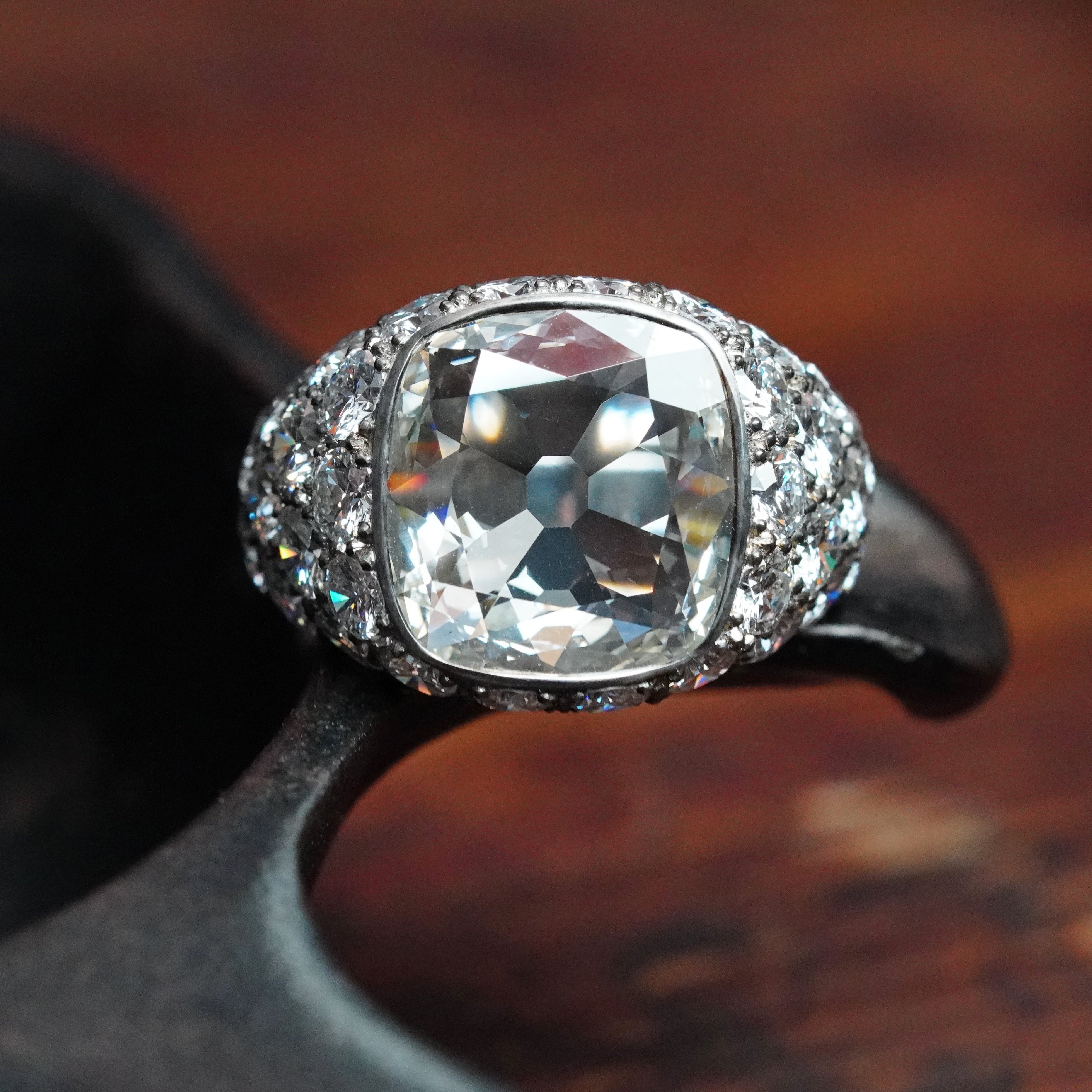 A stunning 3.11 ct cushion-cut white diamond ring, crafted by Jogani in platinum, bezel-set with accent diamonds, offering elegance and timeless allure.