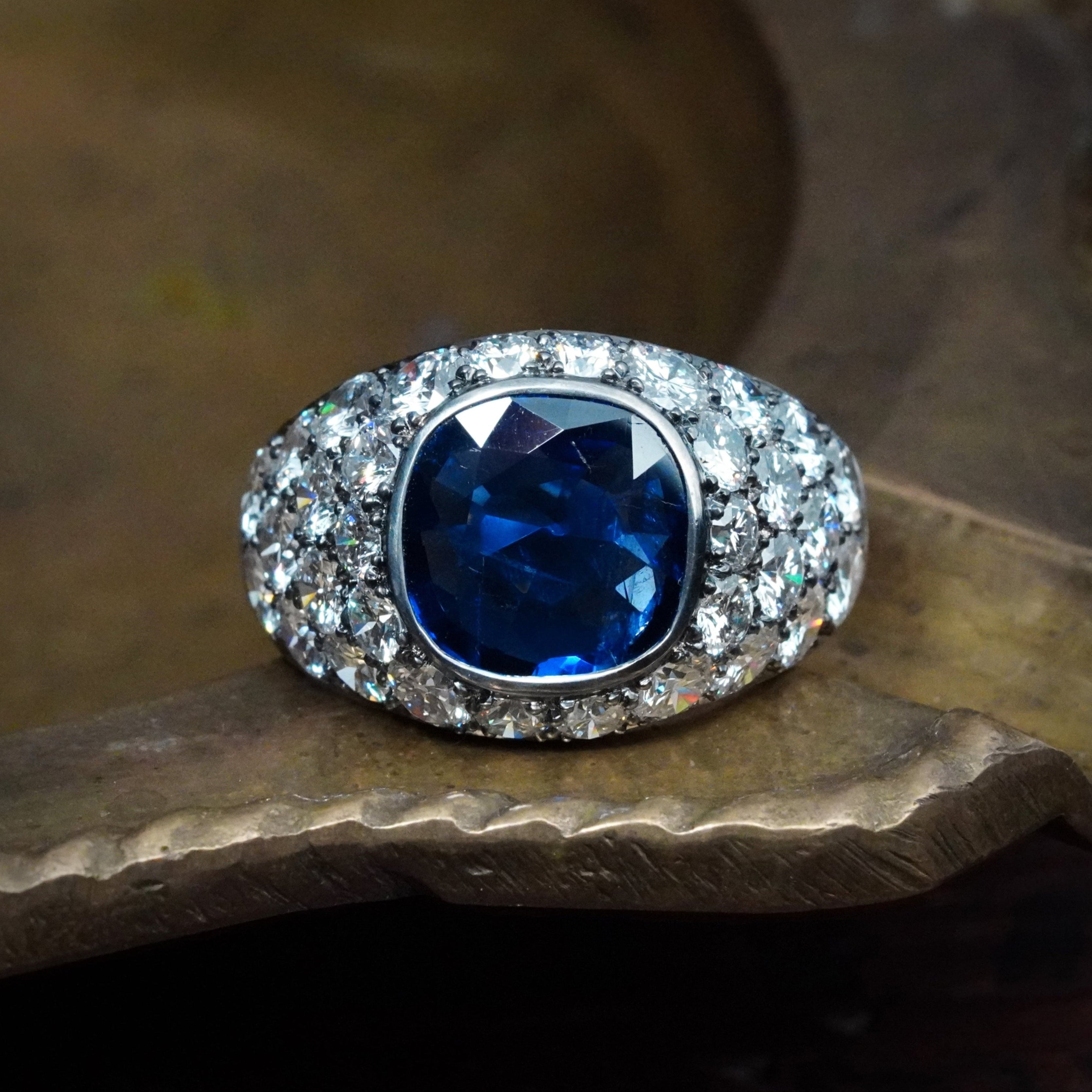 A remarkable 3.39 ct cushion-cut Burma sapphire ring, bezel-set in platinum with dazzling diamond accent cluster, crafted by Jogani for true connoisseurs.