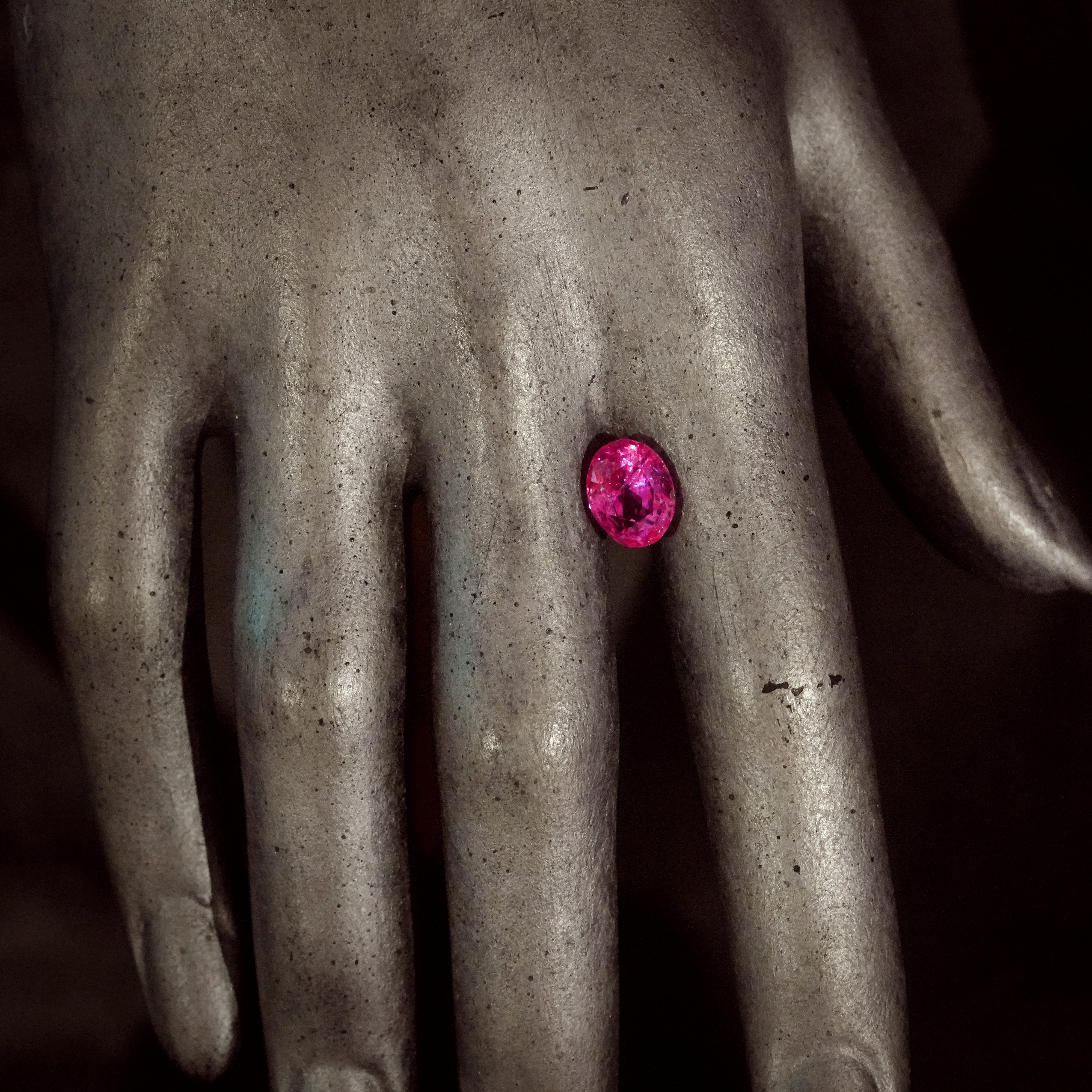 A 4.56-carat oval-shaped Ceylon Padparadscha sapphire, featuring a clean orangy-pink to pink-orange color, dimensions of 9.89 x 7.86 x 6.69 mm, with no evidence of heat treatment, and AGL certificate number 1144014, worn on a hand, presented by Jogani.