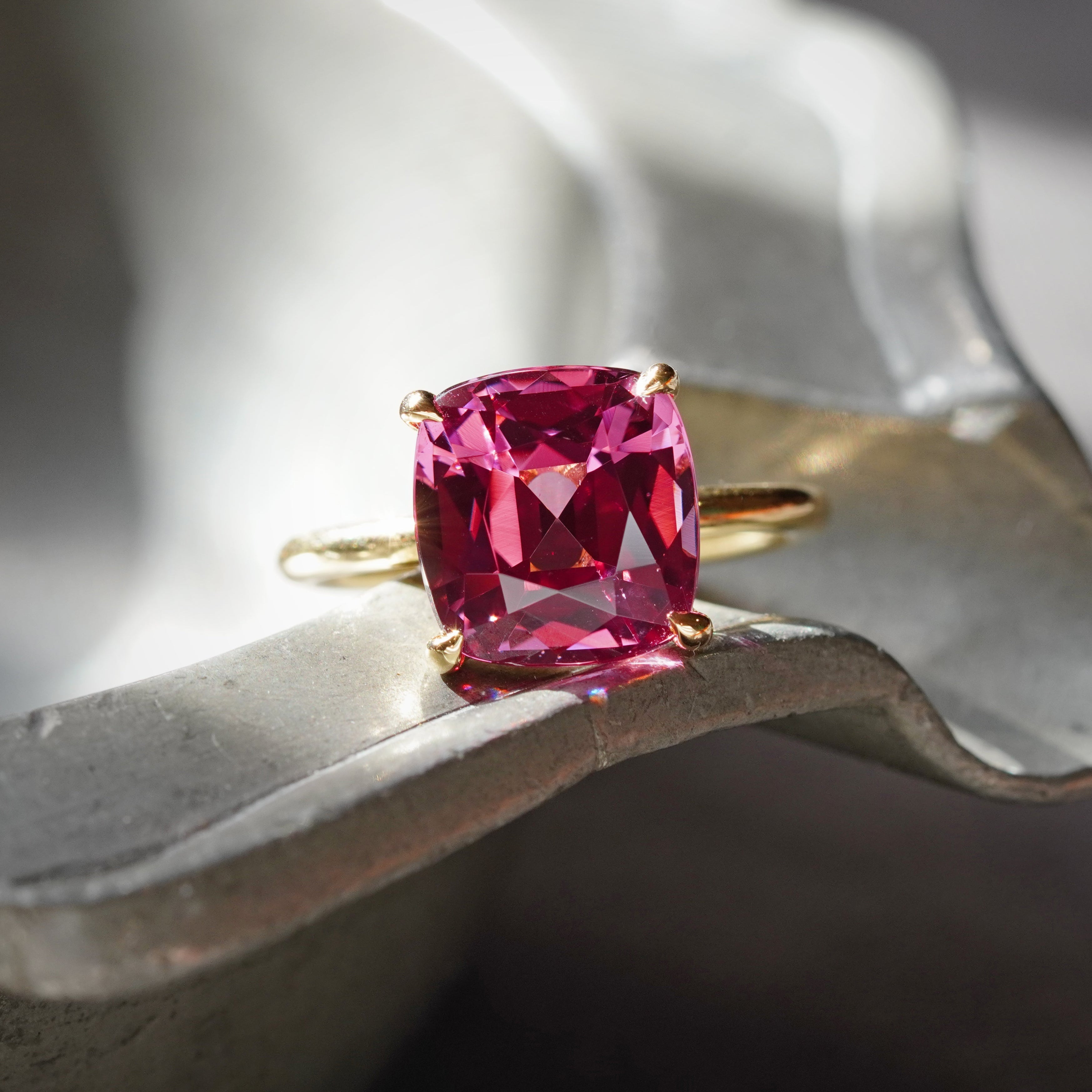 A mesmerizing pink cushion-cut Burma spinel (5.76 ct) set in a refined 18K gold prong setting. This exceptional gemstone, sourced and sold by Jogani, exudes sophistication.