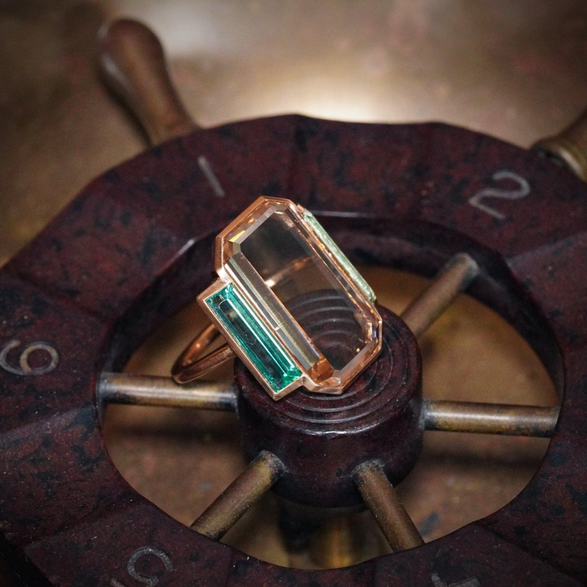 A luxurious 7.13 ct fancy yellowish-brown portrait-cut diamond, set in 20K rose gold and flanked by emeralds. A rare Deco-inspired masterpiece, sourced by Jogani.