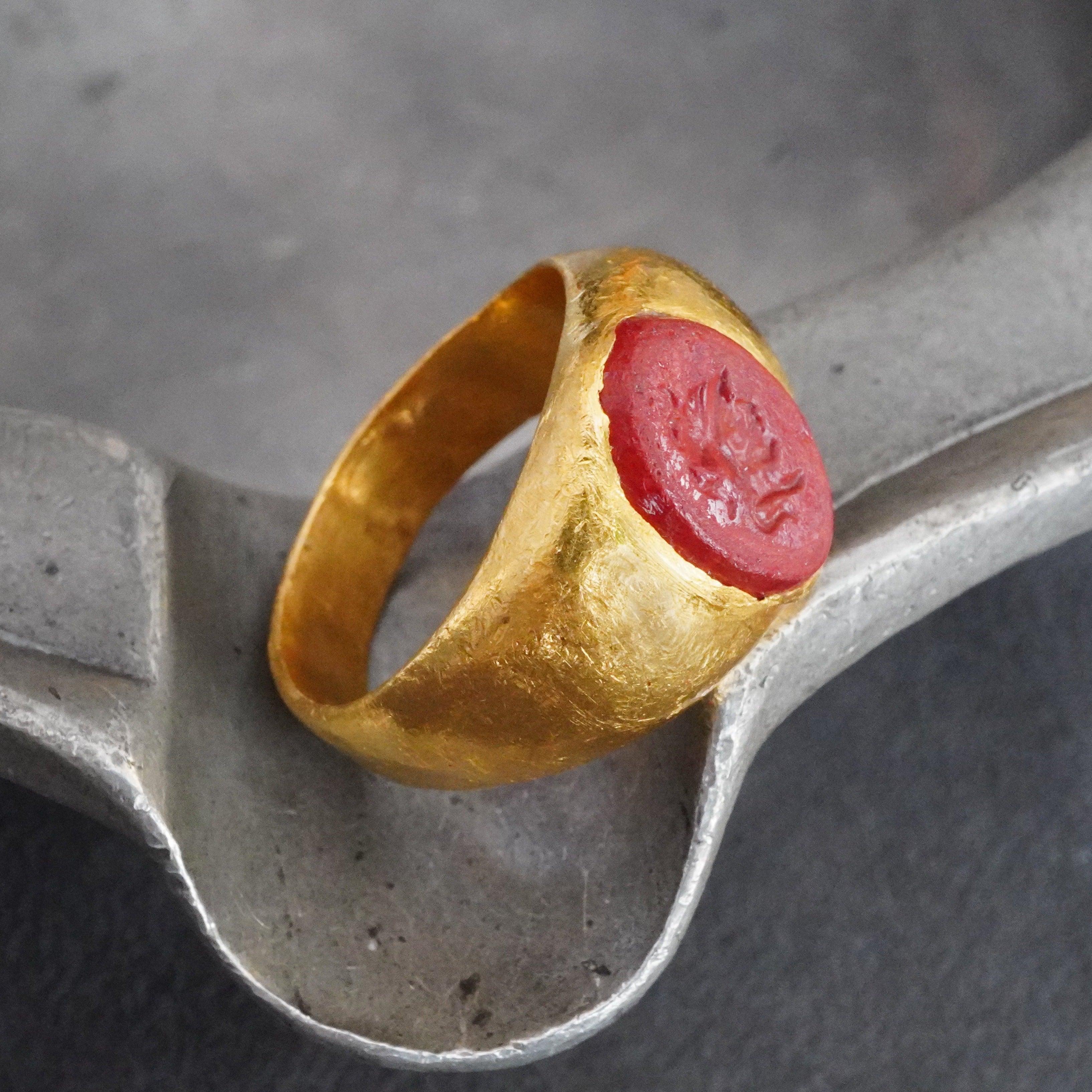 This rare red ancient engraved stone ring, set in luxurious 24K gold, features a striking intaglio design, possibly depicting a Roman soldier—proudly offered by Jogani.