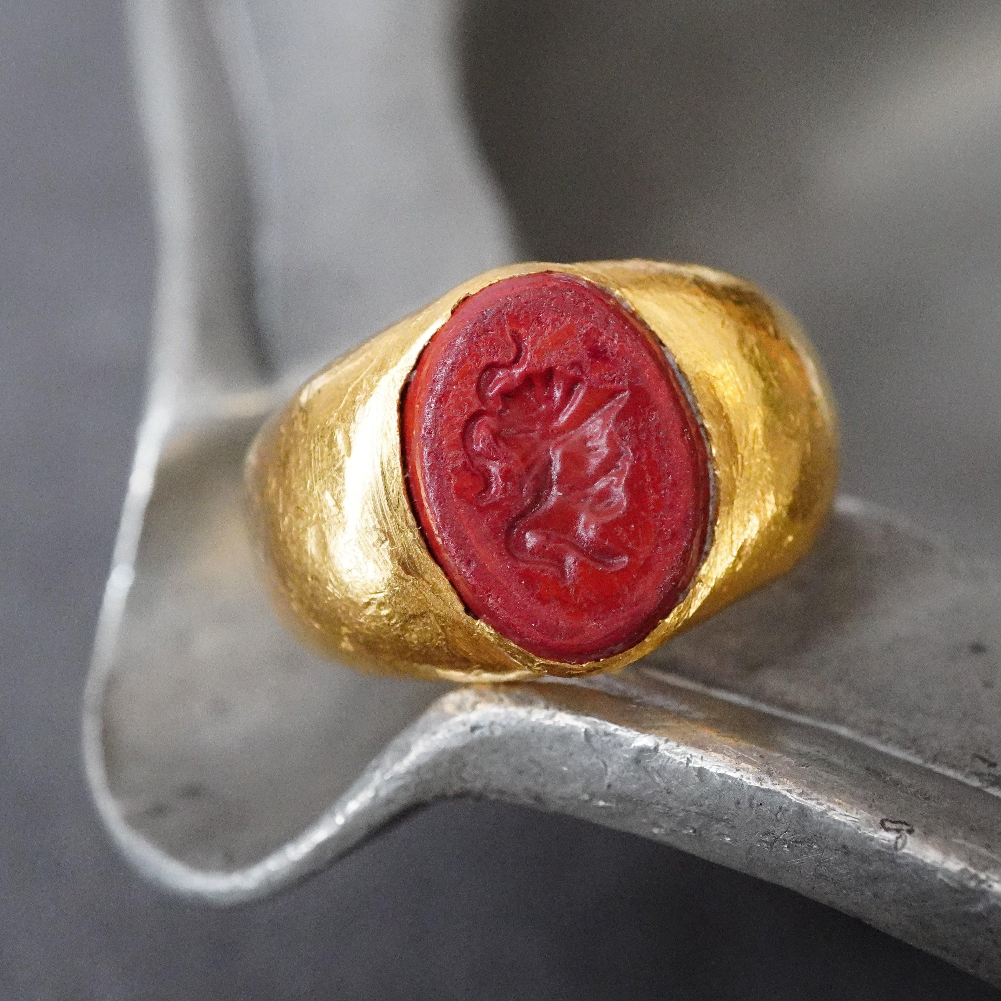 An extraordinary ancient oval engraved stone signet ring set in 24K yellow gold, showcasing a masterfully carved intaglio—available exclusively at Jogani.