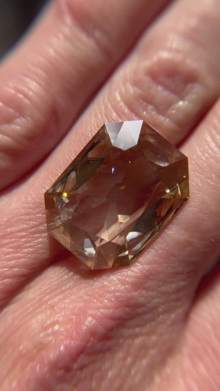 A 13.84-carat step-cut diamond with a fancy brown-yellow color, VVS2 clarity, and type IIa classification, accompanied by a GIA certificate.