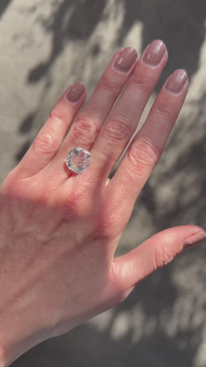 A 5.02-carat cushion-cut diamond with G color and I2 clarity, measuring 12.96 x 12.63 x 4.28 mm, accompanied by GIA certificate number 5231488524, presented by Jogani, displayed on a hand under sunlight.