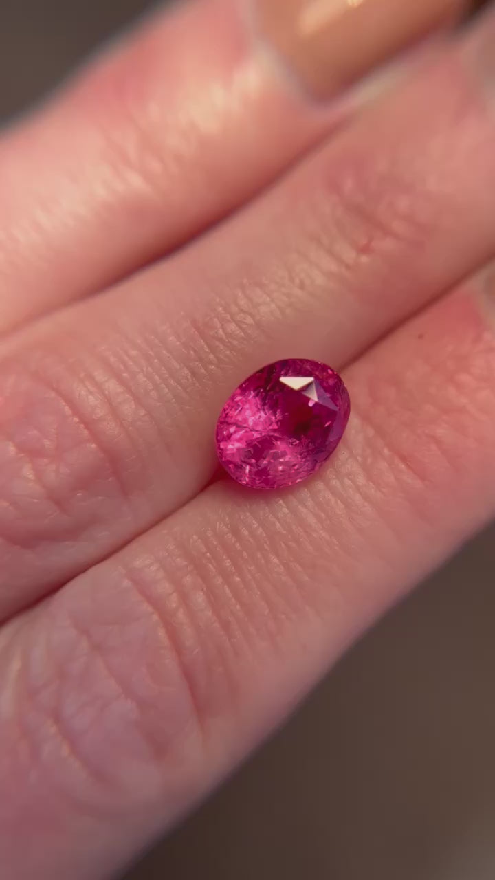 A 4.56-carat oval-shaped Ceylon Padparadscha sapphire, featuring a clean orangy-pink to pink-orange color, dimensions of 9.89 x 7.86 x 6.69 mm, with no evidence of heat treatment, and AGL certificate number 1144014, shown on a hand, presented by Jogani.