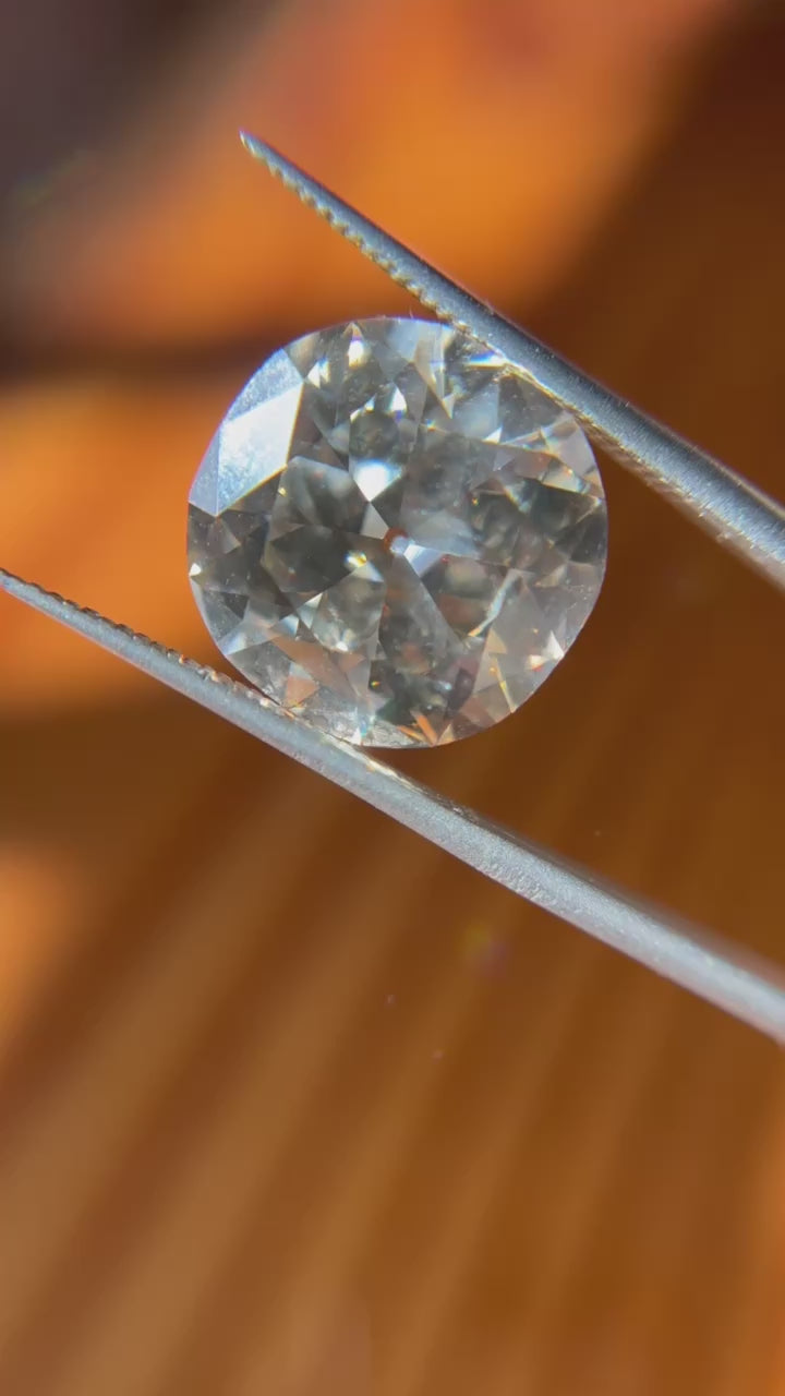 A breathtaking 12.21 ct cushion cut colored diamond sparkling brilliantly under natural sunlight, showcasing its exceptional fire, brilliance, and unique hue.