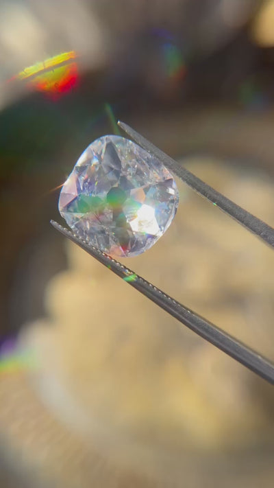 A 5.02-carat cushion-cut diamond with G color and I2 clarity, measuring 12.96 x 12.63 x 4.28 mm, accompanied by GIA certificate number 5231488524, presented by Jogani, displayed in a video held by tweezers under sunlight.